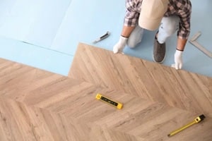 worker installing laminated wooden floor indoors, above view